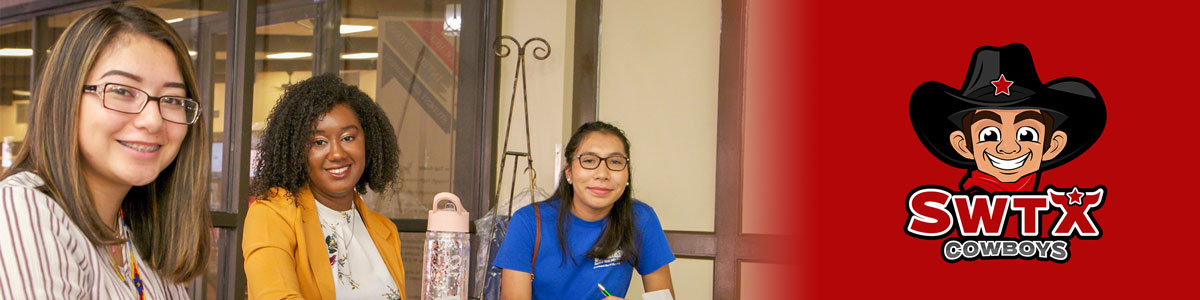 Three students sit at a table smiling at camera